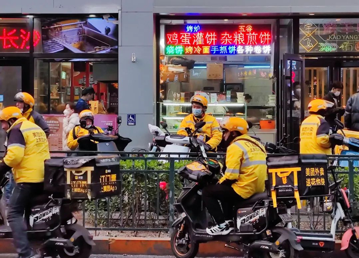 在快餐小吃店铺前等着取餐的骑手。图源：中国新闻网