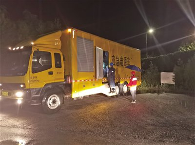 7月31日，国网北京门头沟供电公司员工赵璠、孙智力冒雨检查应急电源车运行情况，做好应急抢修准备。渠洪刚 摄