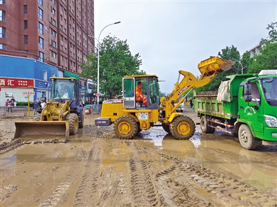 8月1日，门头沟区新桥南大街，来自西城区的支援人员利用铲车将主干路上堆积的淤泥铲掉运走。