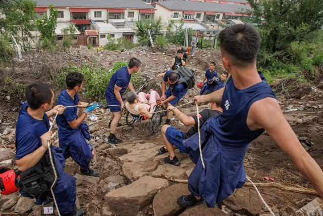 8月2日，门头沟水峪嘴村附近山上，北京消防的队员们转运行动困难的老人。新京报记者 王子诚 摄