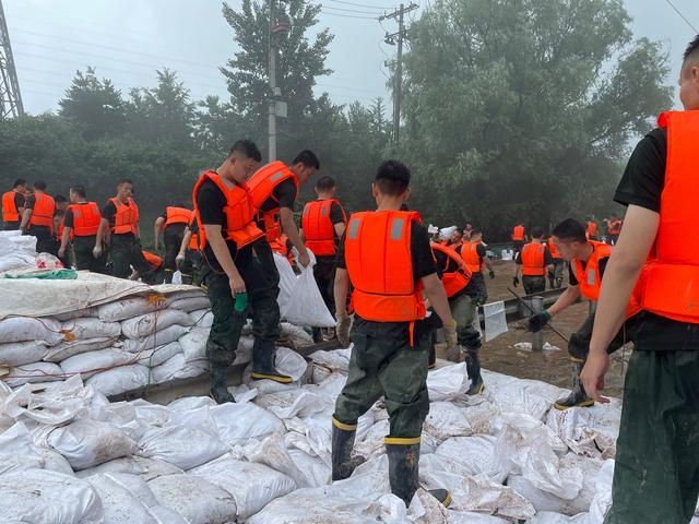 8月1日13时许，武警北京总队官兵于京原漫水桥装填、搬运用于筑堤坝的沙袋。新京报记者 熊丽欣 摄