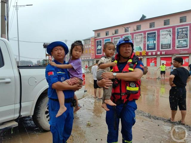 ▲8月3日上午，天津宝坻红十字蓝天救援队队员高扬、李克伦抱起被困儿童走到安全地带。 图片来源/上游新闻记者 张锦