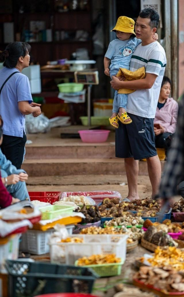 来自湖南邵阳的游客邓磊在云南木水花野生菌交易中心购买野生菌（7月27日摄）。新华社记者 江文耀 摄