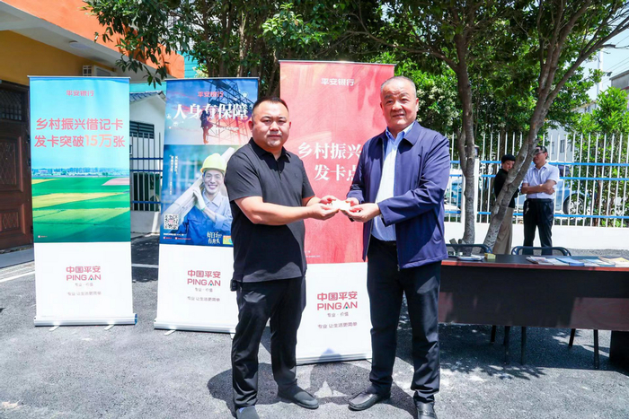 马明哲亲手将第15万张乡村振兴卡交到一位白郢村村民手中。