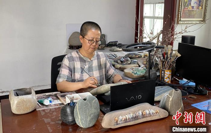 图为马玉兰正在工作室里绘制黄河石画。高莹 摄