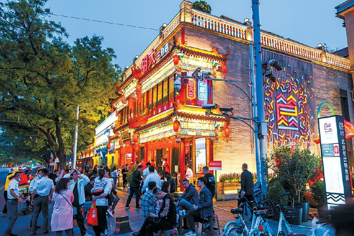 入夜后的簋街胡大饭馆门前坐满排队等位的食客。 邓伟 摄