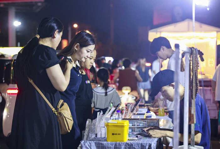 大学生创业专区一处手机贴膜摊位前，顾客排队等候。尹明晓摄