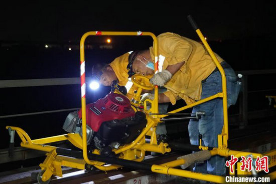 图为南宁工务段职工在湘桂线下行红水河桥上进行钢轨打磨前检查打磨机。宋彤波 摄