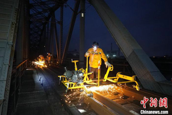 图为南宁工务段职工在湘桂线下行红水河桥上进行钢轨打磨作业。宋彤波 摄