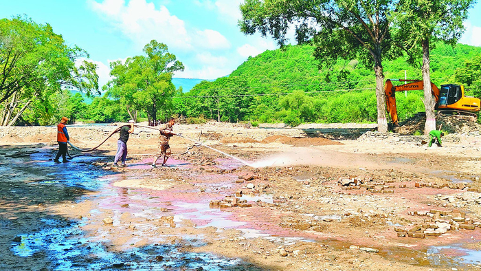  冲洗地面淤泥。    本报记者 李健摄