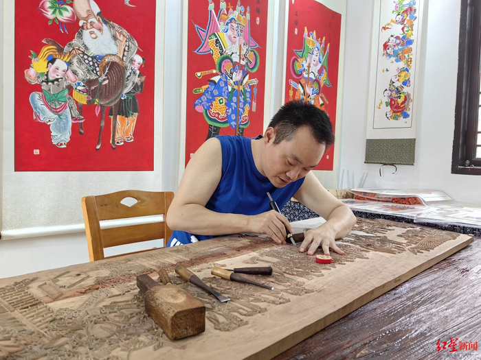 ▲陈刚正在雕刻《迎春图》木版年画