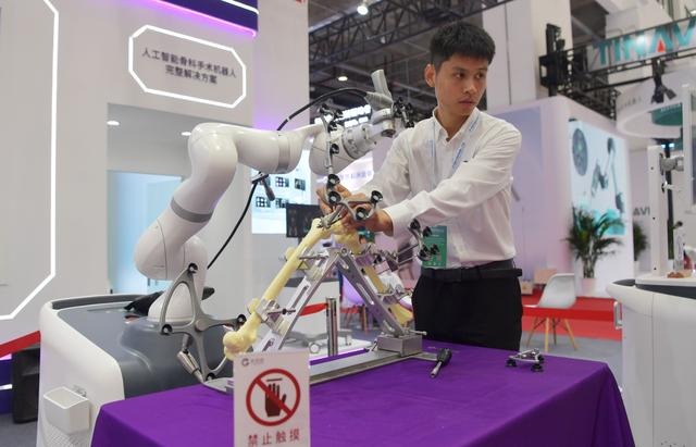 8月16日，2023世界机器人大会现场，工作人员在演示骨科手术机器人。  新京报记者 李木易 摄