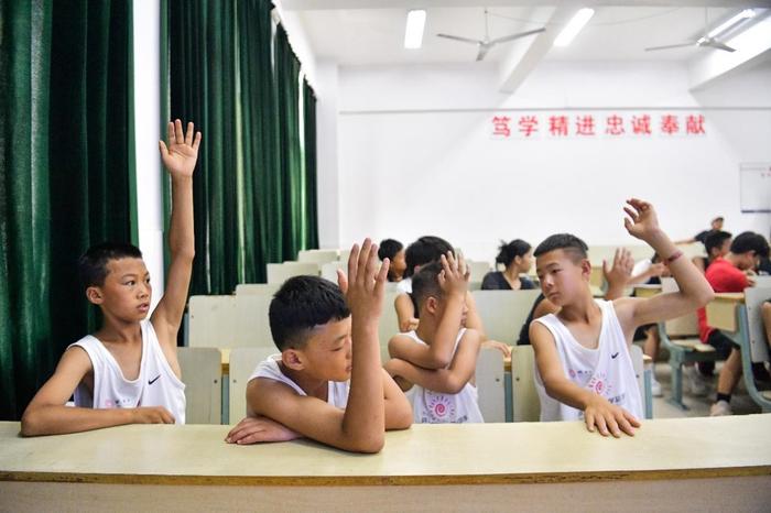 孩子们在课堂上踊跃举手回答提问