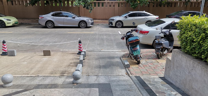 图为长平西街上的小区出入口因为违停车辆盲区加大。