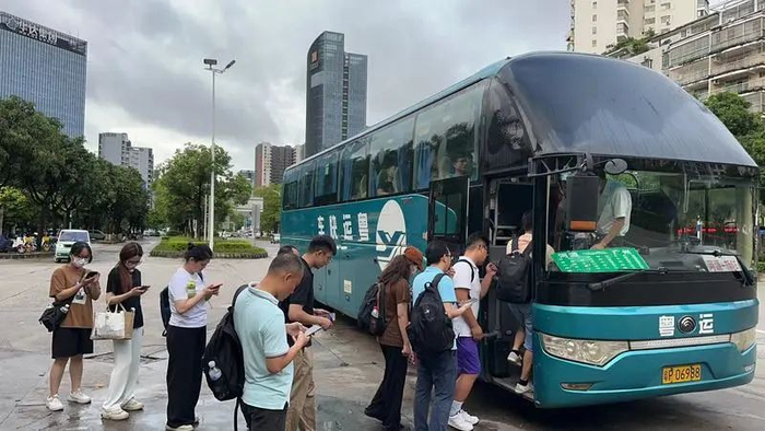 ▲河源粤运滴滴站点巴士上车点，乘客们正在排队上车。