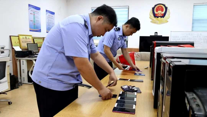 图为办案民警清点、整理查扣的作案手机和电脑