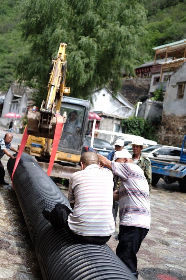 8月25日，爨底下村党支部书记韩跃和村民一起拼接排水管。新京报记者 曹晶瑞 摄