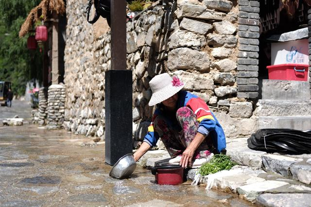 8月25日，村民在路上洗菜，路上流下来的都是山泉水。新京报记者 曹晶瑞 摄