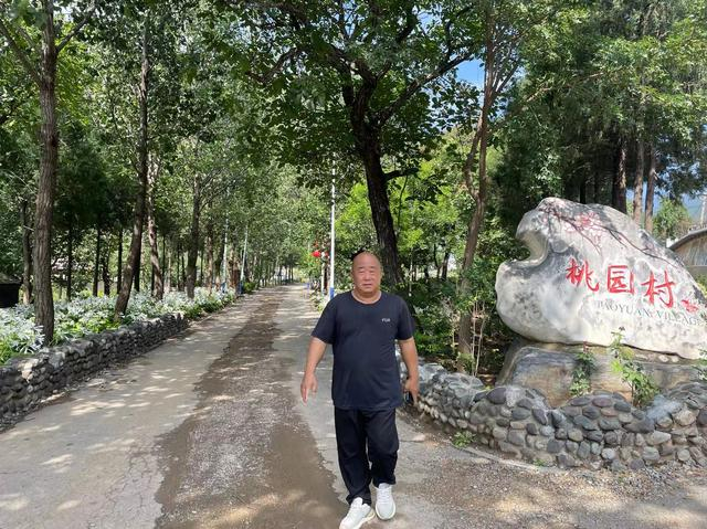 8月25日，桃园村，村支书曹振刚走在村里，村旁小路有玉簪花盛开，村里生活已基本恢复正常。新京报记者 赵利新 摄