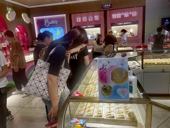 图为消费者在菜百挑选黄金饰品。
