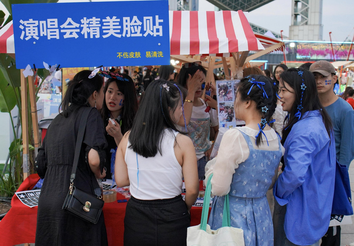 张杰鸟巢演唱会当天，场馆外的妆造摊位上，商家正在给年轻的歌迷做精美脸贴。李伟/摄