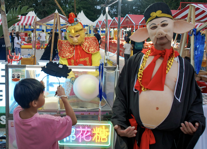 鸟巢观景大道两侧生意红火，“孙悟空”卖棉花糖，“猪八戒”负责招揽生意。李伟/摄