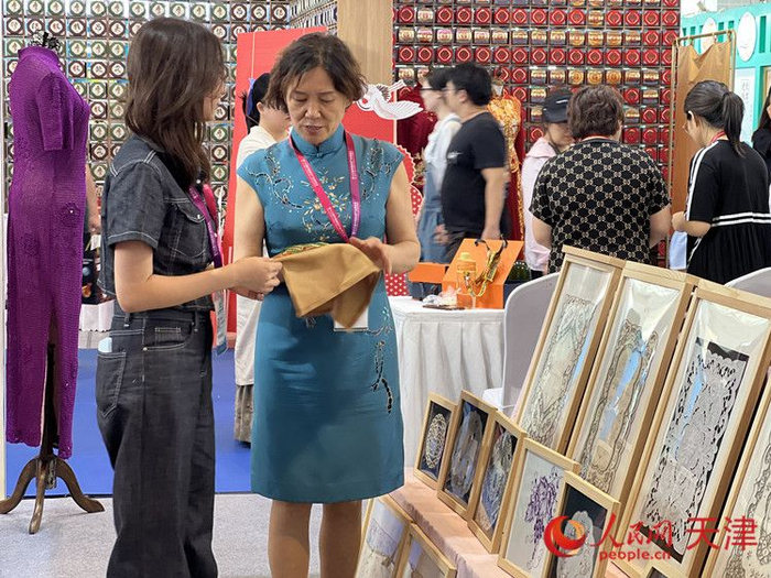 展会上，王玉与女儿就一件展品进行交流。人民网记者 孙翼飞摄