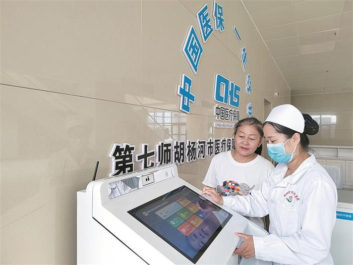     8月31日，七师胡杨河市人民医院护士帮助患者使用兵团医疗保障公共服务自助终端系统办理报销业务。    兵团日报常驻记者  张西安  摄