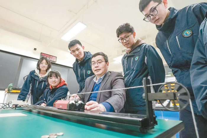 在北京八十中雄安容东分校物理实验室内，胡友永和学生们一起做力学实验。本报记者 武亦彬摄