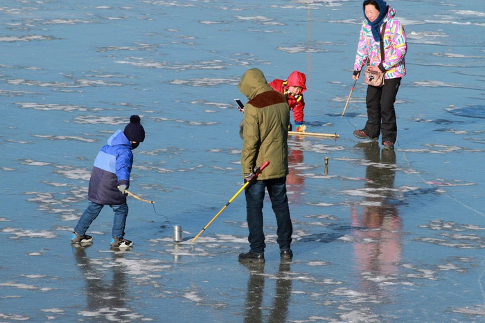 △哈尔滨松花江冰面上，儿童抽冰尜（gá）。
