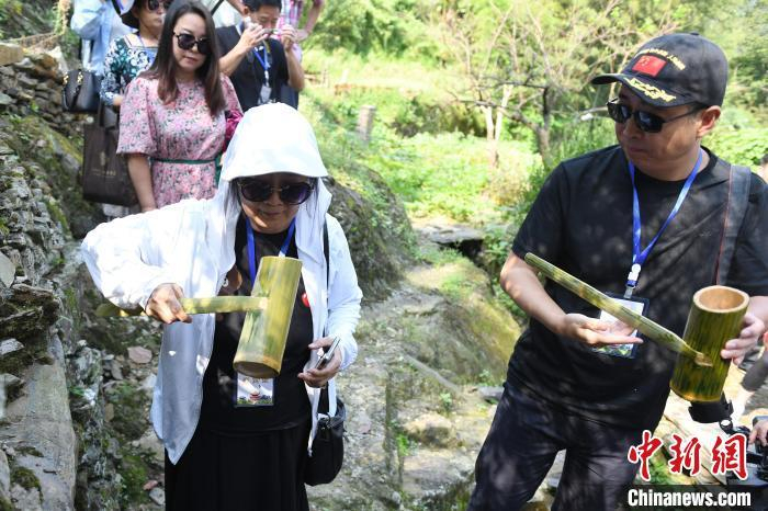 华媒代表拿竹筒品尝山泉水。　中新网记者 杨华峰 摄