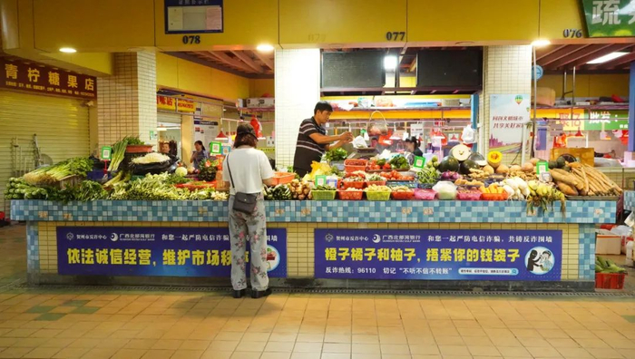 图为八步区中心市场摊位上张贴的反诈宣传标语