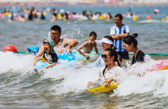 众多游客、市民在威海国际海水浴场戏水纳凉。