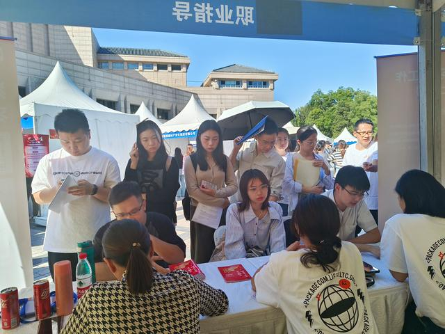 招聘会现场，职业指导和政策咨询台也备受毕业生欢迎。图为工作人员和学生正在就求职的相关问题进行交流。  新京报记者 叶红梅 摄