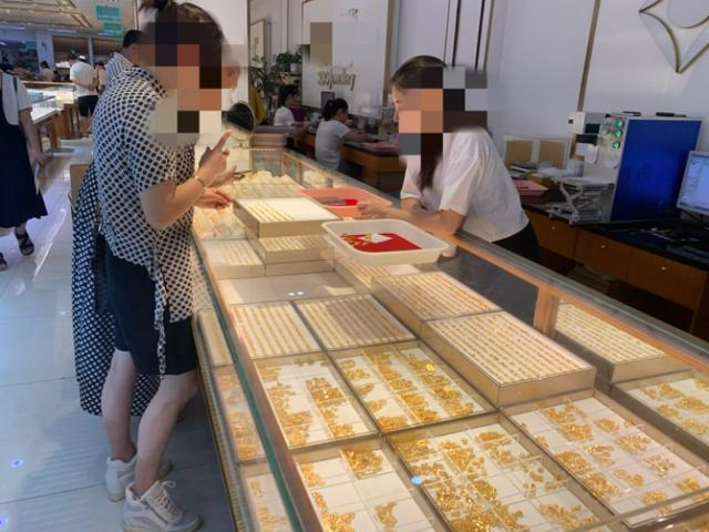 △消费者选购黄金饰品。图片来源 潮新闻