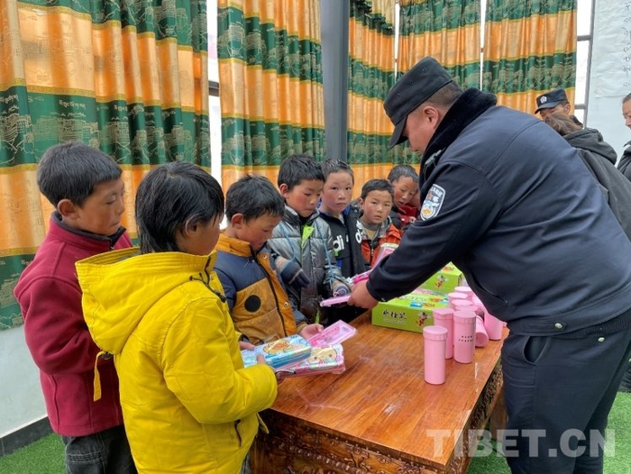 图为先遣乡派出所民警为当地小学生发放学习工具