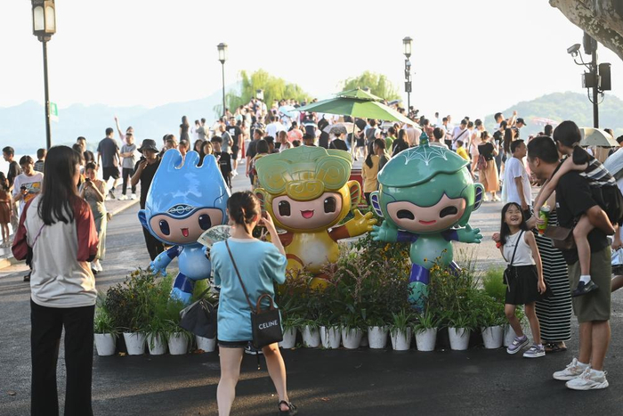 　　游客在位于杭州西湖景区的断桥边与杭州亚运会吉祥物合影。新华社记者 黄宗治 摄