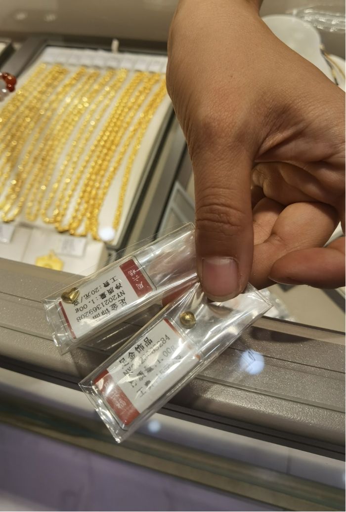 图为一门店销售人员展示金豆产品。新华社记者马晓媛 摄