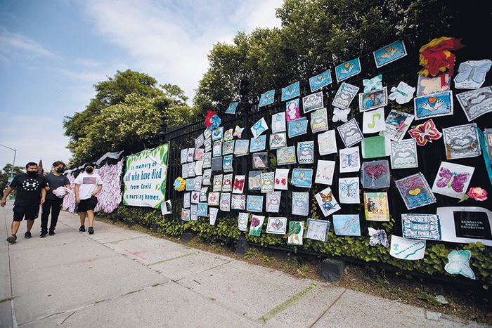 行人从美国纽约一处墓地外为新冠死者设立的纪念装置旁走过（2021 年 6 月 14 日摄）王迎摄 / 本刊