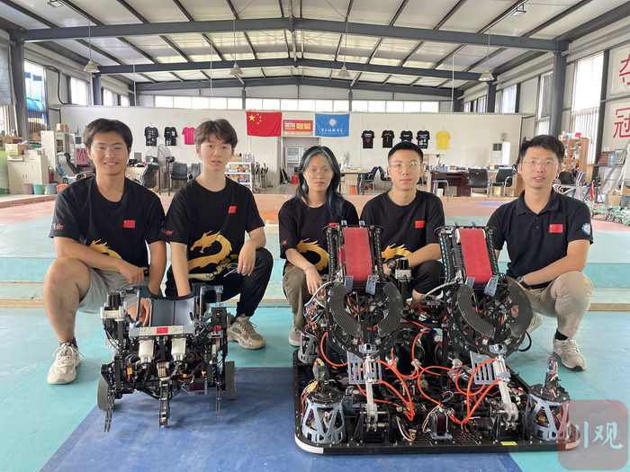 在训练基地，教练吴军（右一）和队员、参赛的机器人一起，左边是“小兔”机器人，右边是“大象”机器人。钟帆 摄