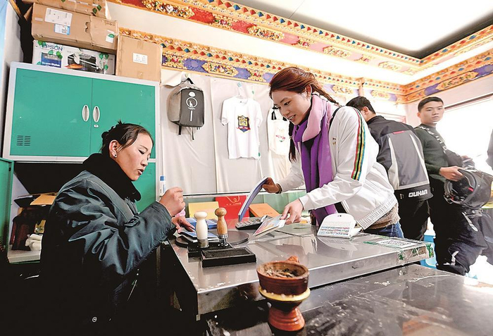     “天上西藏”邮局珠峰店工作人员措姆正在给游客准备邮寄的明信片盖戳。    本报记者 田福良 摄