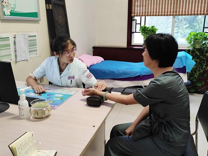 中医科主任陆亚男正在为一位阿姨把脉