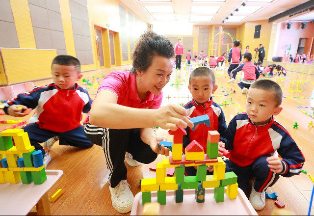 9月15日，敦煌市幼儿园，老师与小朋友一起搭积木。