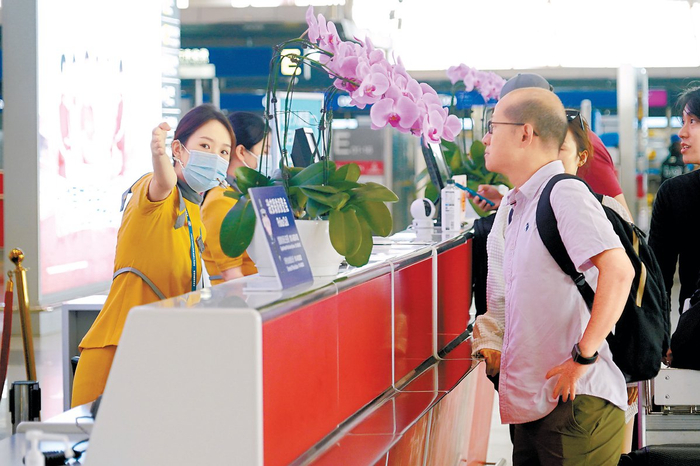 昨天，在首都国际机场，工作人员为出行旅客提供指引服务。本报记者程功摄