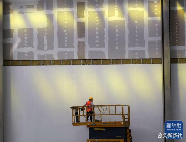 9月30日，中建三局工人在郑州国际铁路港西作业区项目工地操作升降车，准备进行防火墙涂料施工作业。新华社记者 李嘉南 摄