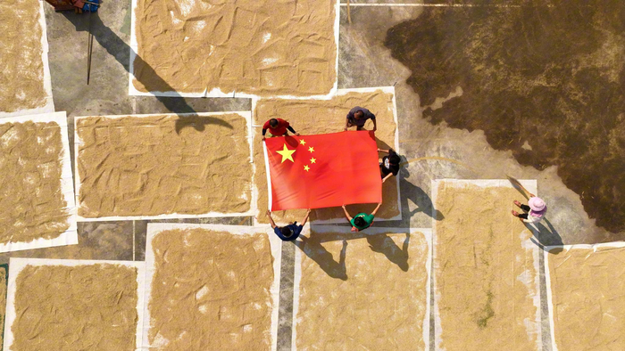 9月24日，榕江县朗洞镇岑最村，干群自发在金黄的晒秋场展示国旗。吴化雨 摄