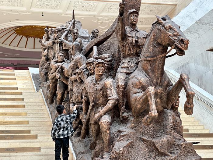 图为小游客参观以“军垦魂”为主题的雕塑。