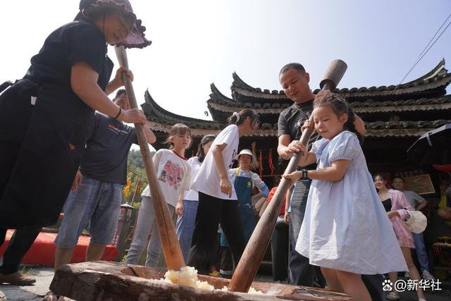 ↑10月2日，游客在湖南省怀化市通道侗族自治县双江镇芋头村体验打糍粑。新华社发（吴三东 摄）