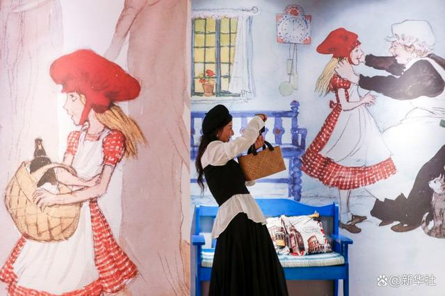 ↑10月2日，一名女孩在安徽省黄山市屯溪区黎阳老街举行的《世界插画大展》上拍照。新华社发（施亚磊 摄）