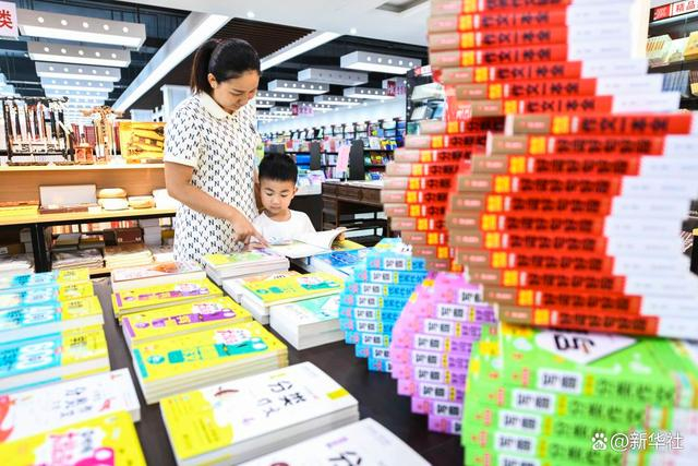 ↑10月2日，家长在湖南省常宁市新华书店给孩子讲解书籍内容。新华社发（周秀鱼春 摄）